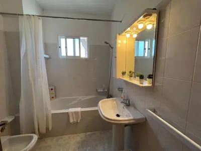 a bathroom with a sink and a tub and a mirror at Beach Relax Apartment in Porto Santo
