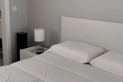 a bed with white sheets and a lamp on a table at 'A Bucha' by The Cliff Coast in Paul do Mar