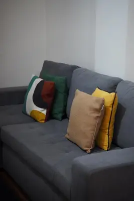 a gray couch with colorful pillows on it at Serenity Apartment - Free Parking in Santa Cruz
