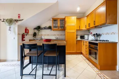 a kitchen with wooden cabinets and a island with bar stools at Casa Keira in Luz