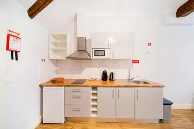 a kitchen with white cabinets and a wooden counter top at Casa na Ilha II in Funchal