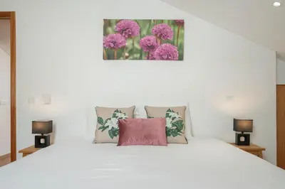 a bedroom with a white bed with pink pillows at Casa Strelitzia by An Island Apart in Funchal