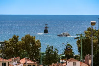 a ship in the ocean with a boat in the water at Casa Strelitzia by An Island Apart in Funchal