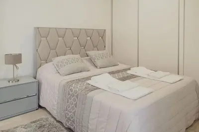 a white bedroom with a large bed with two towels on it at Casa Estrelicia in Ponta do Sol