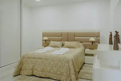 a white bedroom with a large bed with two pillows at Casa Estrelicia in Ponta do Sol
