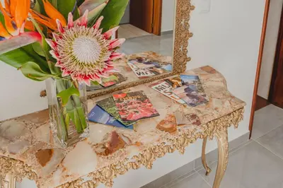a table with a vase of flowers and a mirror at Casa Estrelicia in Ponta do Sol