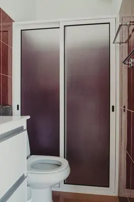 a bathroom with a toilet and a glass shower door at Casa Estrelicia in Ponta do Sol
