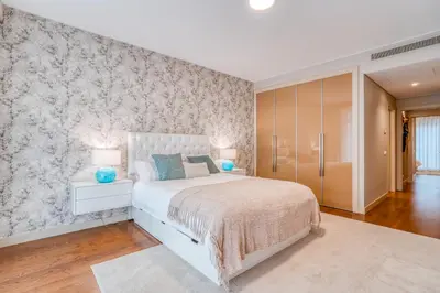 a bedroom with a white bed and a wall at Suite BK - 3 Pools - Gym - AC - Huge Balcony in Funchal