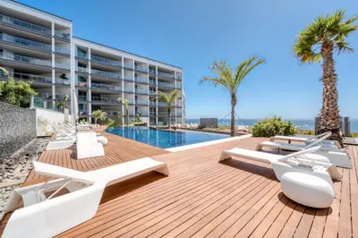 an outdoor deck with lounge chairs and a swimming pool at Suite BK - 3 Pools - Gym - AC - Huge Balcony in Funchal