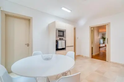 a white dining room with a white table and chairs at Suite BK - 3 Pools - Gym - AC - Huge Balcony in Funchal