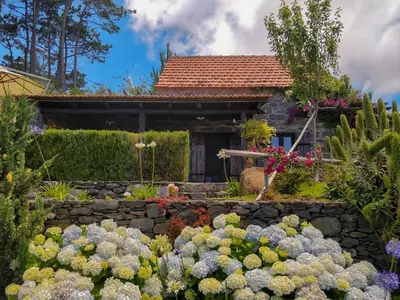 a garden with flowers in front of a house at Achadinha - Mountain Cottage in Arco da Calheta