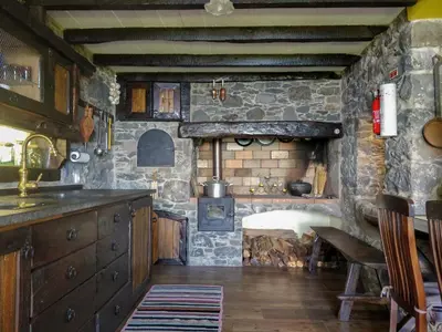 a kitchen with a stove and a stone wall at Achadinha - Mountain Cottage in Arco da Calheta
