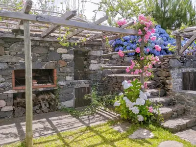 a stone wall with a fireplace and flowers on it at Achadinha - Mountain Cottage in Arco da Calheta