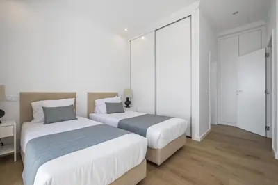 two beds in a bedroom with white walls and wood floors at Casas da Luz by Homie in Ponta do Sol