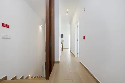a hallway with white walls and a wooden stair case at Casas da Luz by Homie in Ponta do Sol