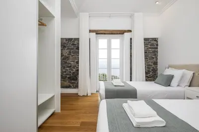 a white bedroom with two beds and a couch at Casas da Luz by Homie in Ponta do Sol