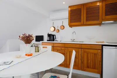 a kitchen with wooden cabinets and a white table at Baldeia - Oceanfront Apartments in Ponta do Sol