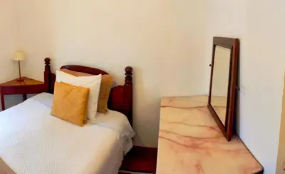 a bedroom with a bed and a mirror on a table at Peaceful place in São Vicente in São Vicente
