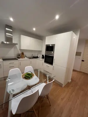 a kitchen with white cabinets and a glass table and chairs at Fatima`s House in Funchal
