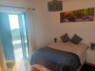 a bedroom with a bed with a view of a balcony at Casa RuMa ao Sol in Ponta do Sol