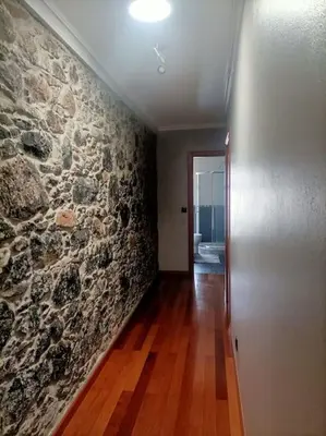 a room with a stone wall and a hallway at Casa RuMa ao Sol in Ponta do Sol