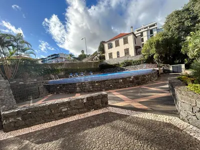 a stone retaining wall with a swimming pool in front of a building at In Town View in Funchal