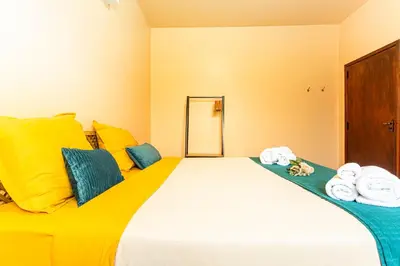 a bed with yellow and blue pillows and towels on it at Home Thomas in Lombada dos Marinheiros