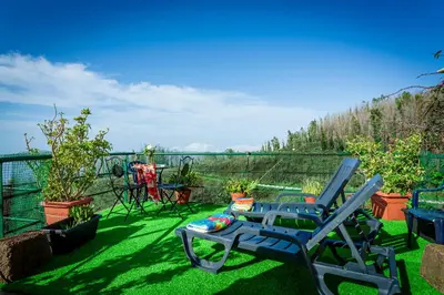 a blue chair sitting on the grass on a balcony at Home Thomas in Lombada dos Marinheiros