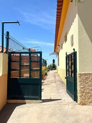 a green gate on a building with a sidewalk at Home Thomas in Lombada dos Marinheiros