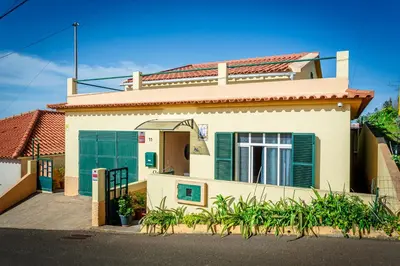 a white house with green doors and a gate at Home Thomas in Lombada dos Marinheiros