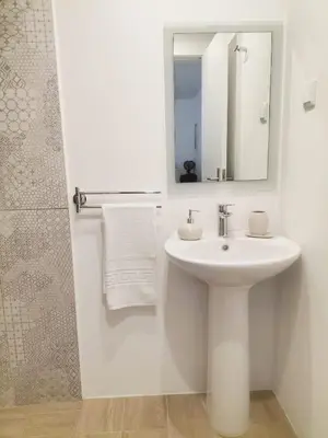 a white bathroom with a sink and a mirror at Vila Loki in Funchal