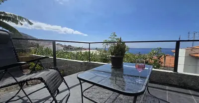 a glass table on a balcony with a view of the ocean at Vila Loki in Funchal
