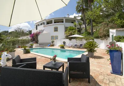 a house with a swimming pool with chairs and an umbrella at LGS32V5 moradia grande conforto, lugar sossegado in Lagos