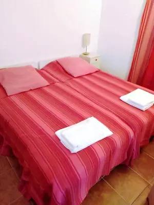 a bed with red sheets and white towels on it at LGS62 V3 casa e jardim a 100mts praia da Luz in Luz