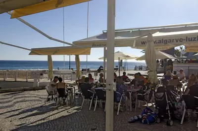 a group of people sitting at tables on the beach at LGS62 V3 casa e jardim a 100mts praia da Luz in Luz
