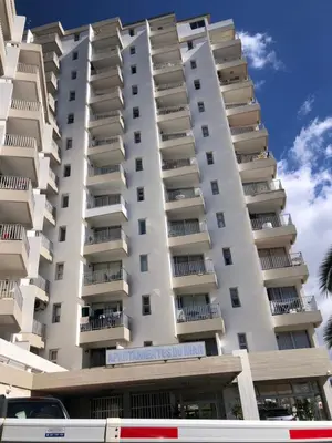 a tall white apartment building with a bus in front of it at Beach Studio Apartment in Funchal