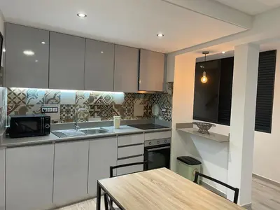 a kitchen with white cabinets and a wooden table at Neves GuestLoft by Madeira Holiday Rentals in Ribeira Brava