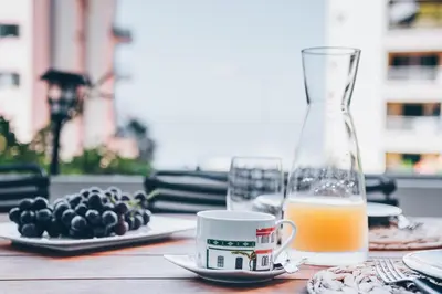 a table with a glass vase and a cup of orange juice at Elephant by Wanderlust Madeira - 2BR Apartment with Terrace, side Sea View and pool access in Funchal
