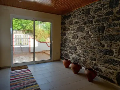 a room with a stone wall and a sliding glass door at Peaceful place in Porto Moniz in Salão