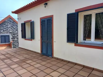 a house with blue shutters and a patio at Peaceful place in Porto Moniz in Salão