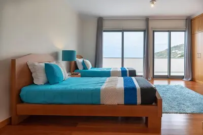 a bedroom with two beds and a large window at Belo Mar in Arco da Calheta