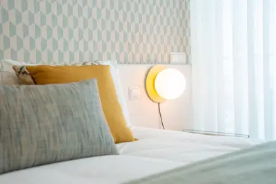 a bed with a pillow and a lamp next to a window at Sea View - 3 Pools - Parking - Gym - Supermarket - Prime Location in Funchal