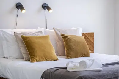 a bed with white sheets and gold pillows at Tower Penthouse by Homie in Funchal