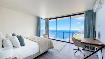 a bedroom with a bed and a desk and a large window at Ohana Ocean View by Lovelystay in Arco da Calheta