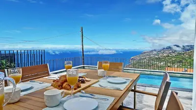 a wooden table with glasses of orange juice on a balcony at Ohana Ocean View by Lovelystay in Arco da Calheta