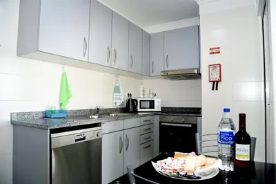 a kitchen with white cabinets and a table with a plate of food at Green Pearl Apartment in Funchal