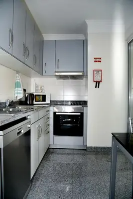 a kitchen with white cabinets and a black appliance at Green Pearl Apartment in Funchal