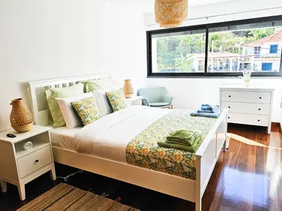 a white bedroom with a bed and a window at Machico Oasis - Mountainview in Machico