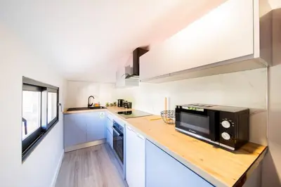a kitchen with white cabinets and a black microwave at Pena View Apartment in Santa Cruz