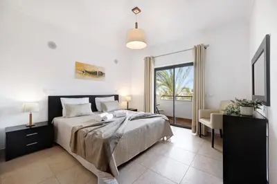 a bedroom with a bed and a desk and a window at Chez Hélène et Paulo - Lagos in Lagos